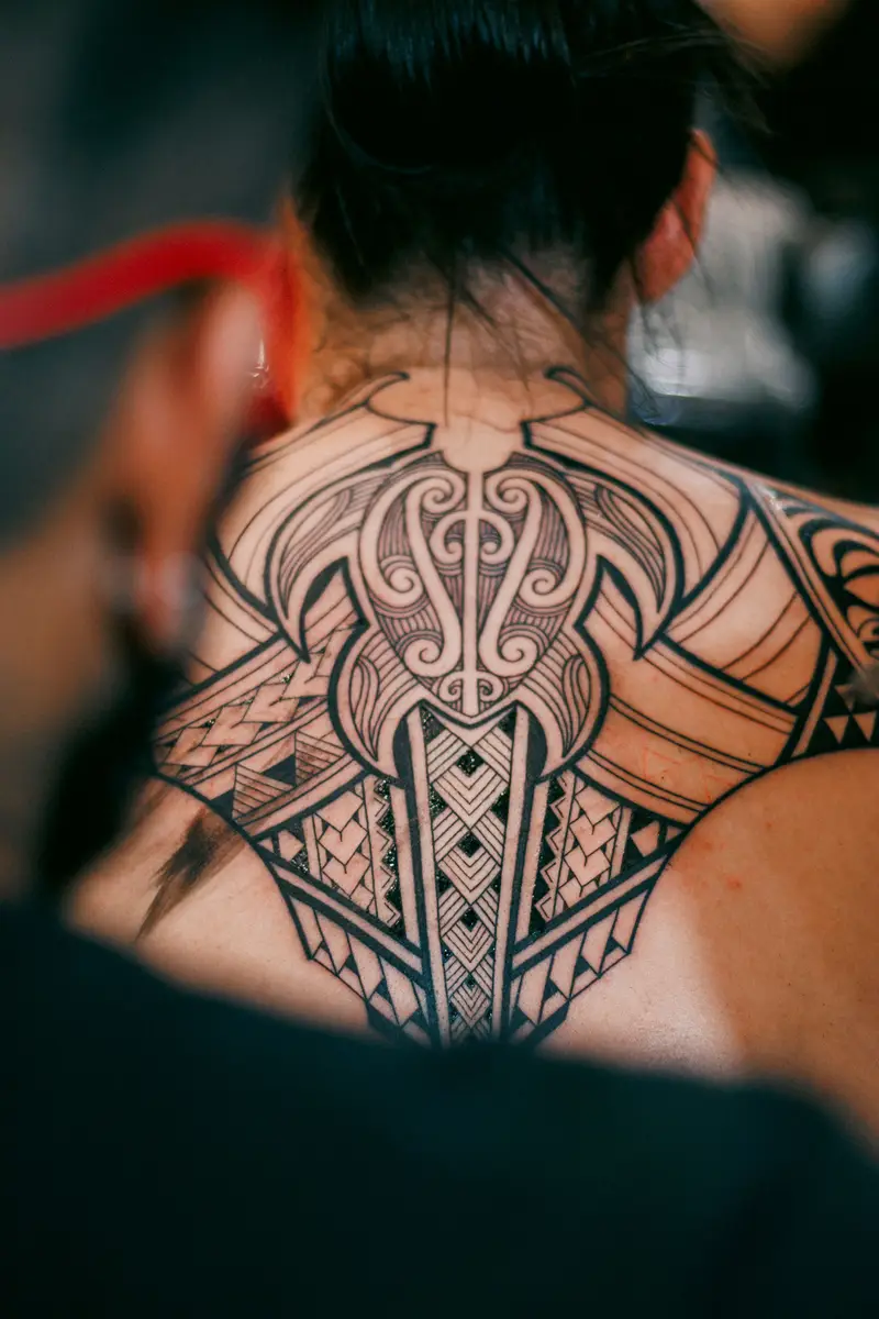 Large symmetrical blackwork pattern across a person's upper back